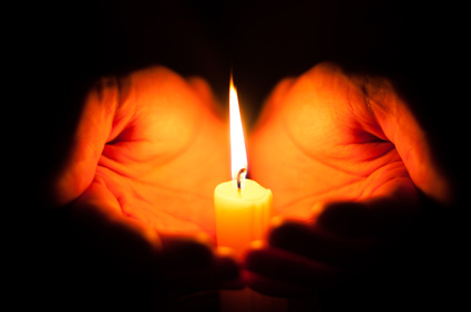 Candle on palms on a black background